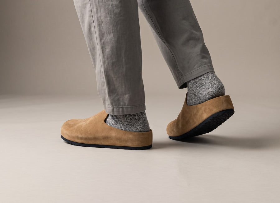 Tan Suede Relief Clogs mid-step, the heel lifting