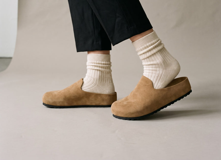 Stepping into a tan Suede Relief Clog through the open back
