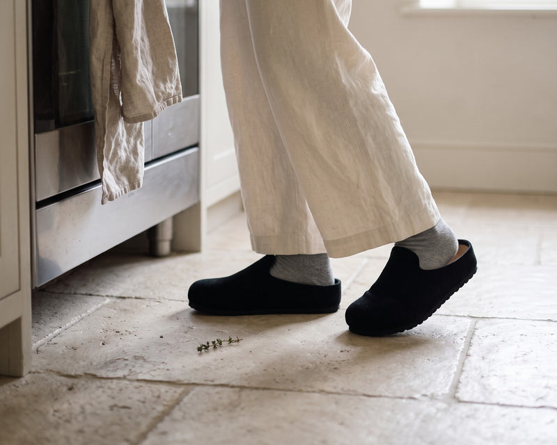Black Suede Relief Clogs on a stone kitchen floor